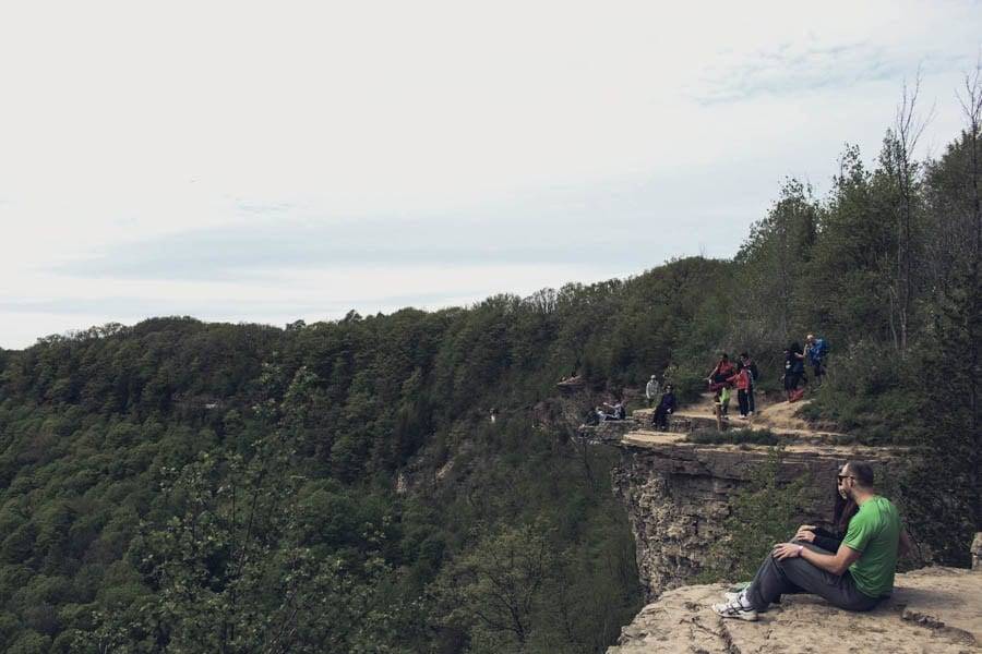 Peak sit on the edge of a cliff and look out at the view.