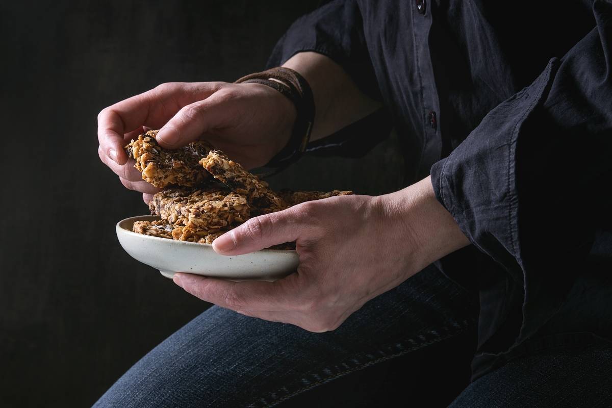A woman picks up cereal bars from a plate.