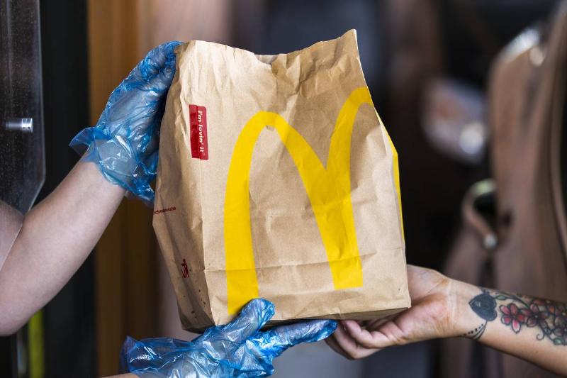 A McDonald's employee hands a customer a to-go bag through the drive-thru.