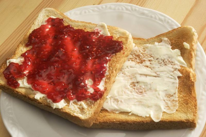 Two slices of toast are covered with jam and butter.