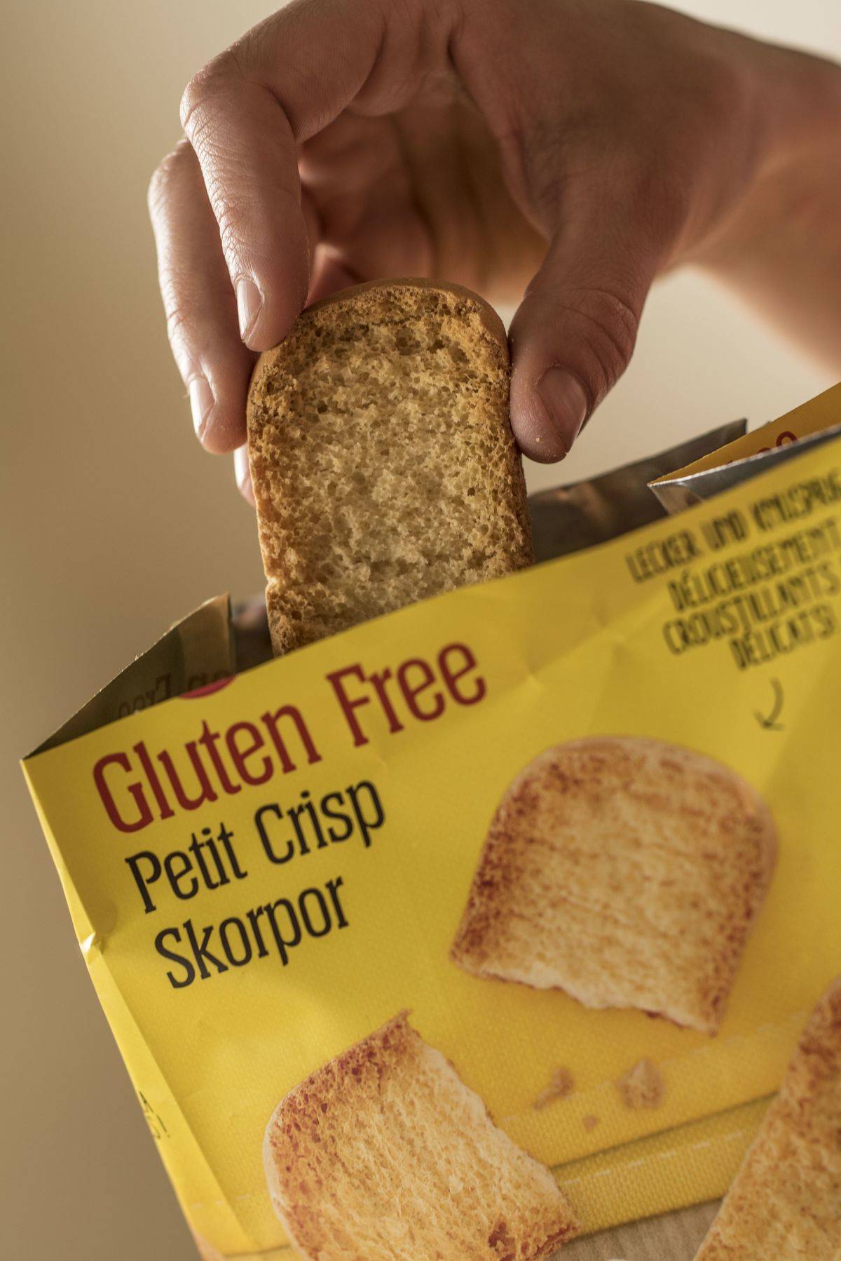 A person removes a gluten-free biscuit from a package.