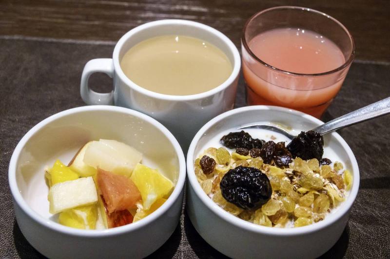 Cereal is served with a bowl of fruit, coffee, and juice.