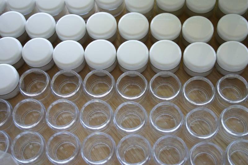 Rows of cosmetic jars are seen with or without lids.