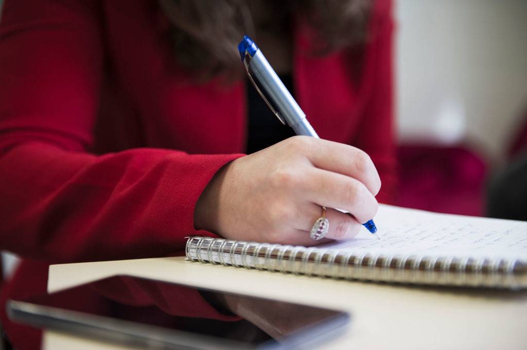 a woman writing down notes in a journal