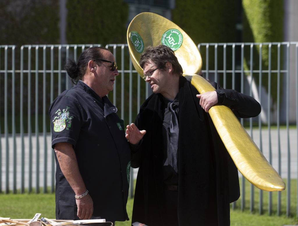 men talking to each other with one holding a large gold spoon