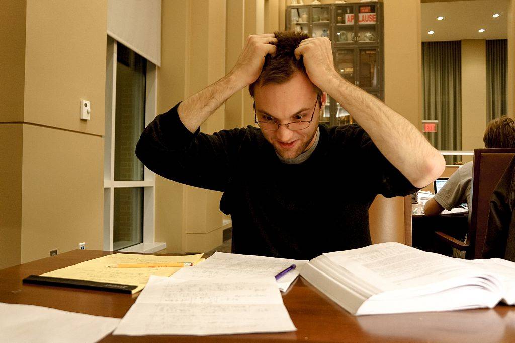 A flustered college student grabs his hair as he looks at his notes
