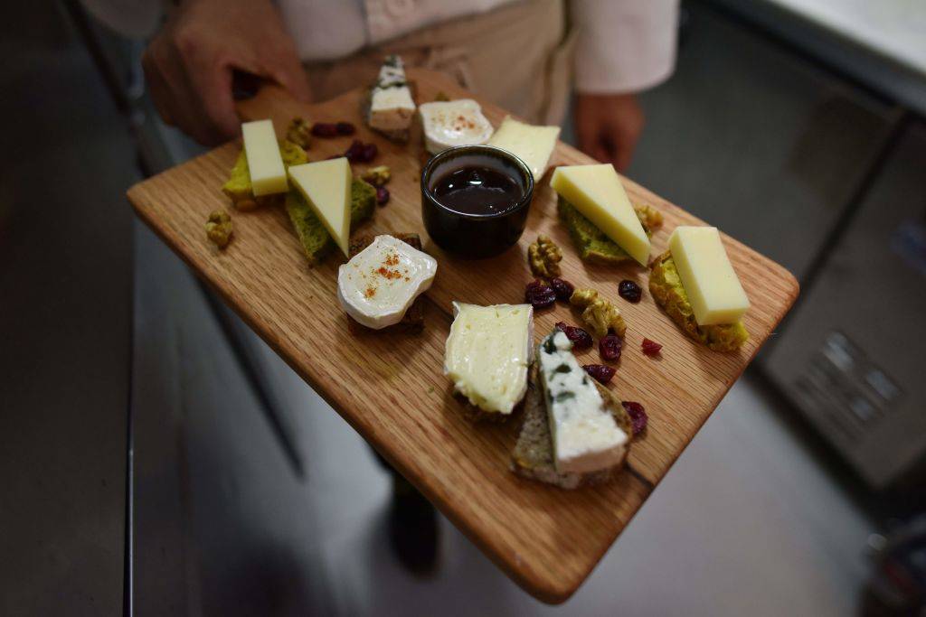 a chef displays a cheese platter featuring French brie