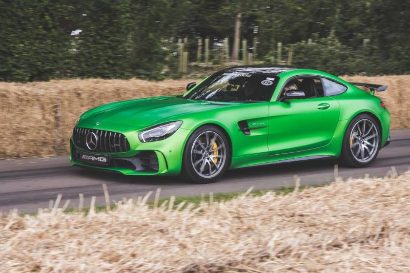 A green Mercedes-AMG GT drives down the road.