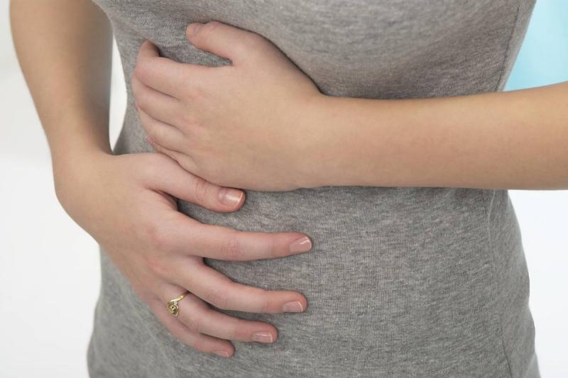 A woman clutches her stomach in pain.
