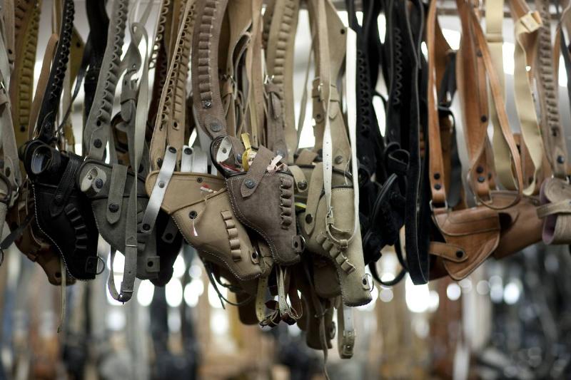 Holsters for sale hang from a rail.
