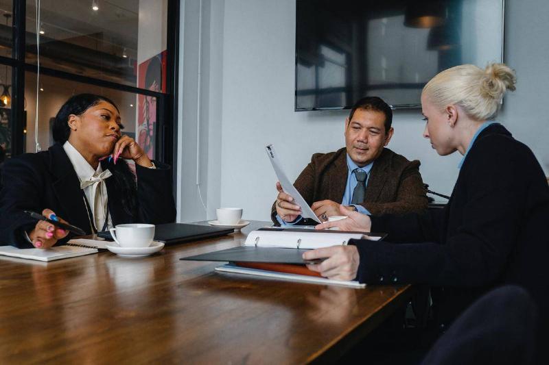 two women and one man at boardroom table