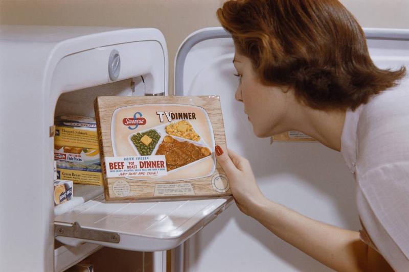Woman pulling a TV dinner out of a freezer