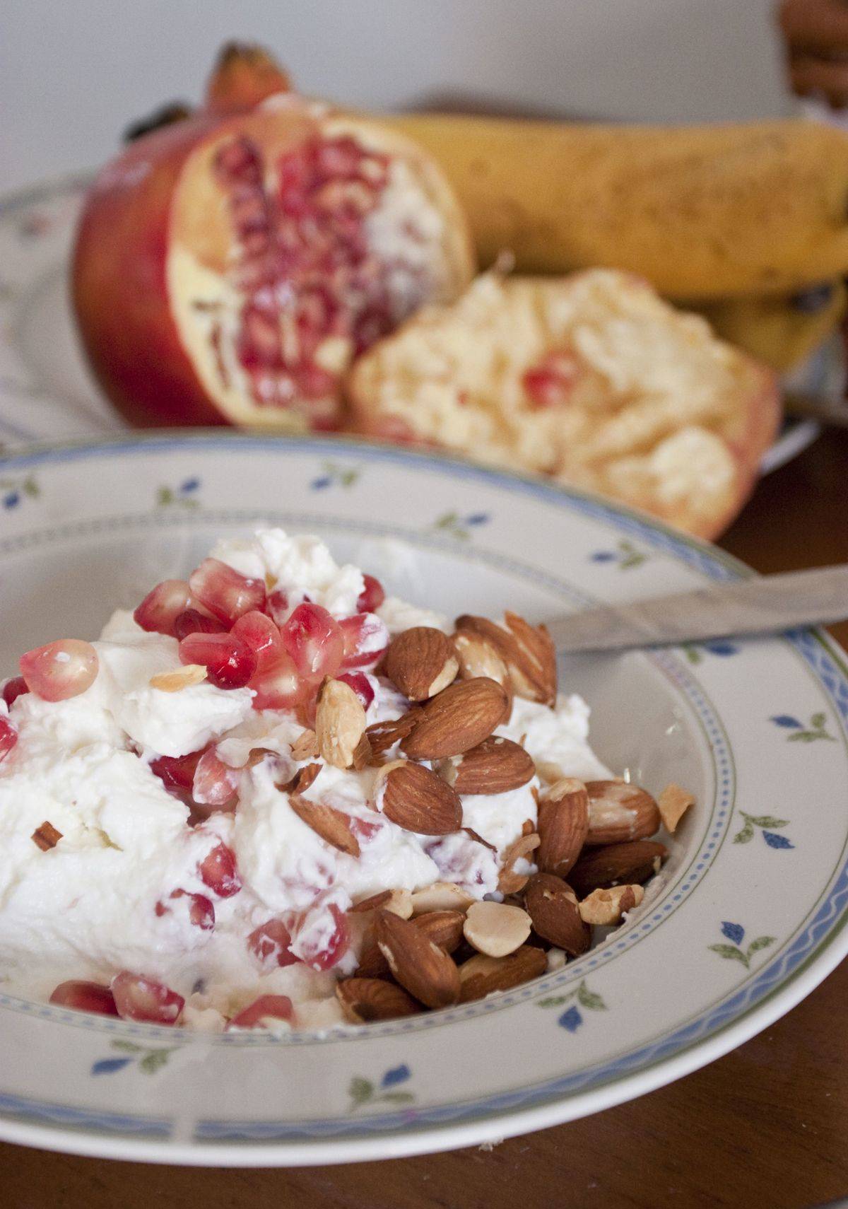 Almonds and pomegranate seeds are in a bowl of yogurt.