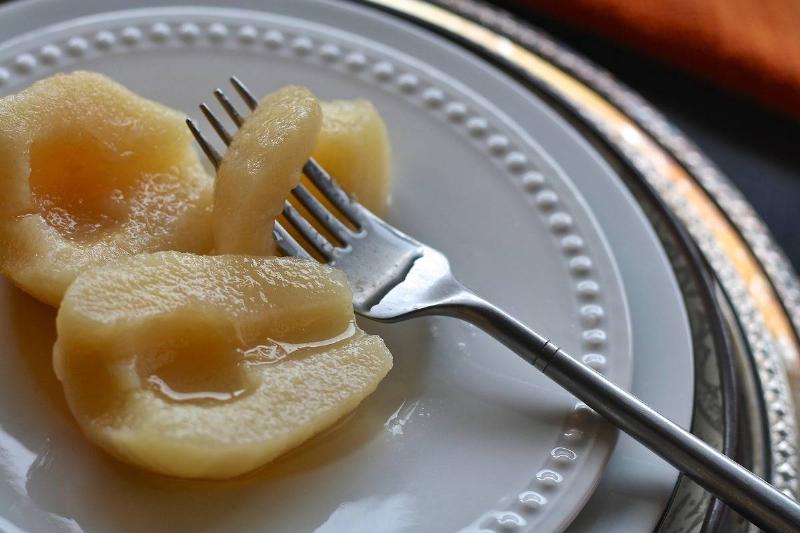 Canned pears sit on a plate with a fork.
