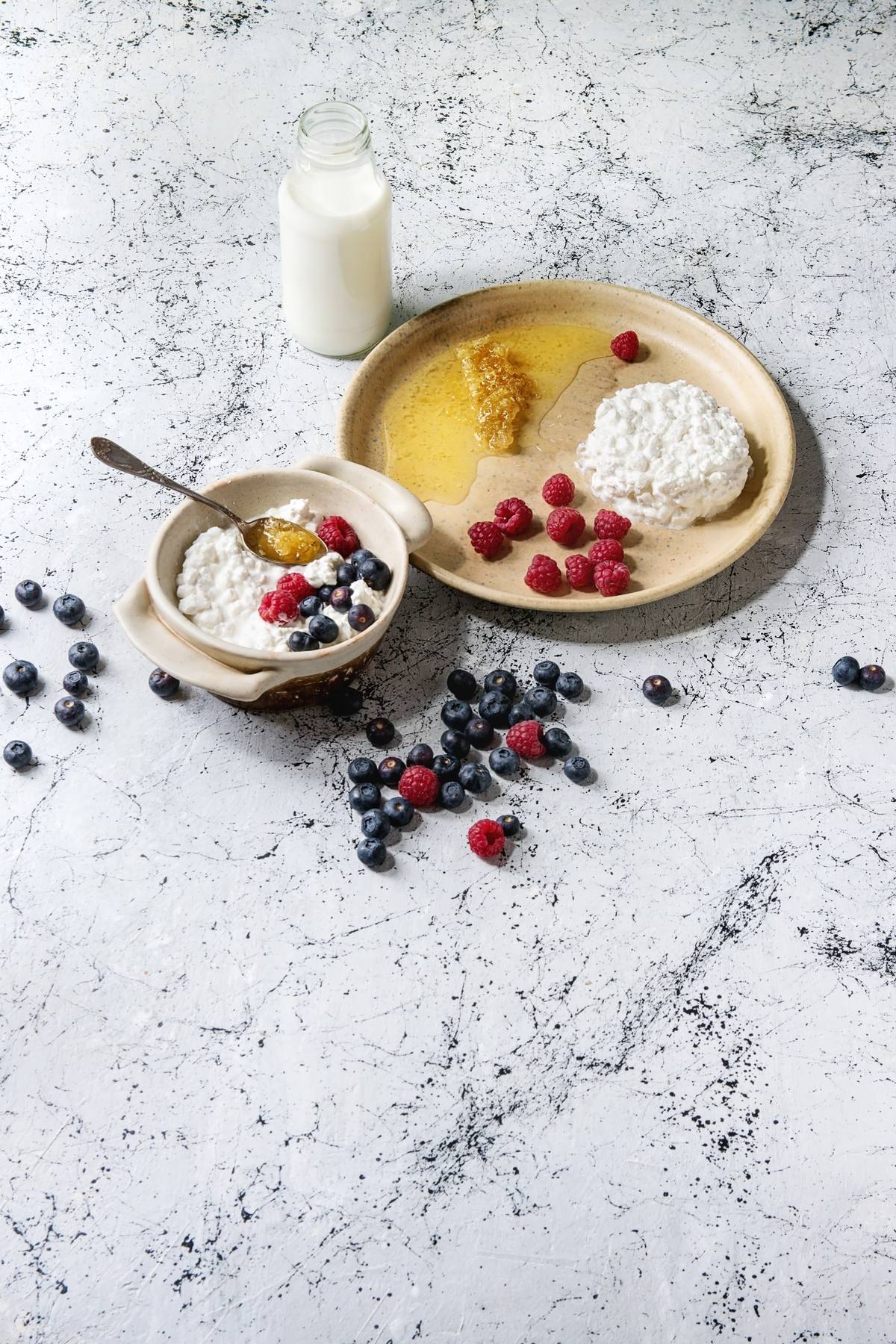 Two ceramic bowls of cottage cheese also feature honey and berries.