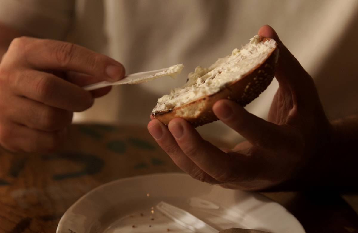 A person spreads cream cheese on a bagel.