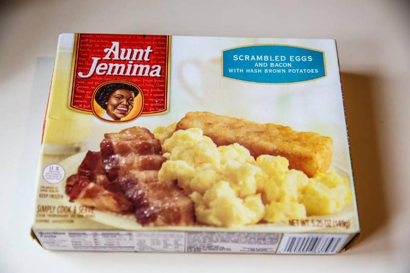 A packaged Aunt Jemima frozen breakfast of eggs and bacon lies on the table.