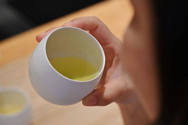 A woman drinks a cup of Japanese green tea.