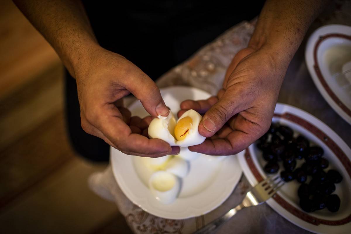 A person pulls apart a hardboiled egg.