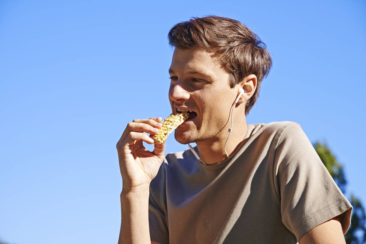 A man eats a granola energy bar.