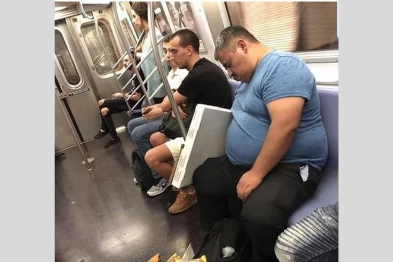 man sleeping on subway with pizza on the floor