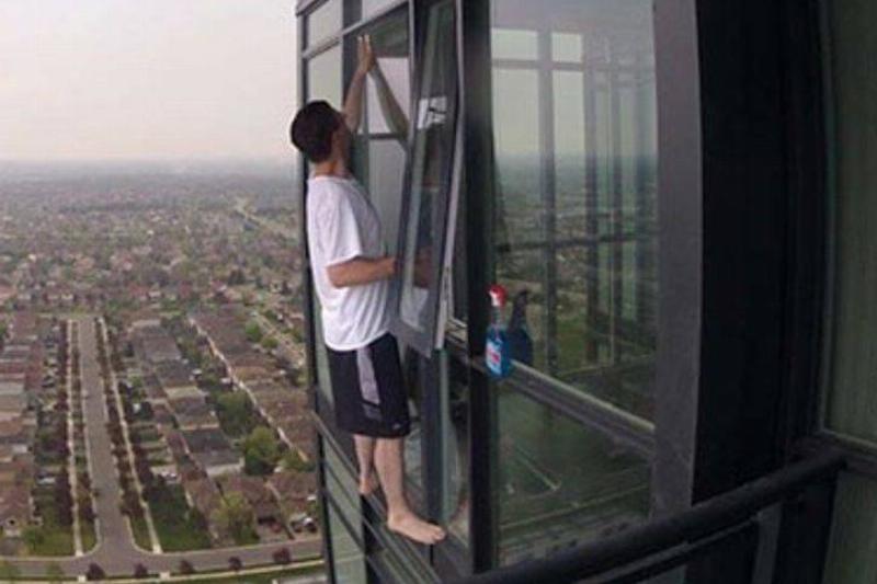 Person cleaning window on high rise building without any safety harness