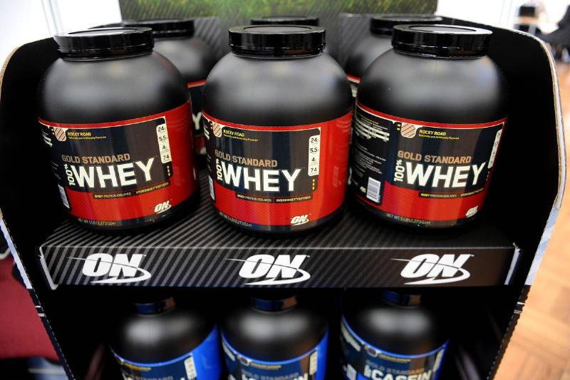 Tubs of whey protein for shakes are for sale on a store shelf.