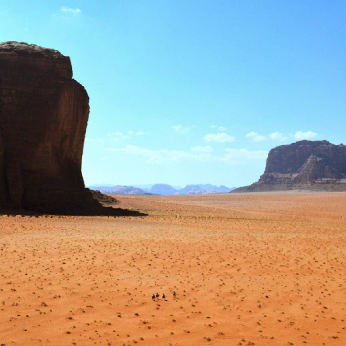 4 people walking in a huge, vast desert