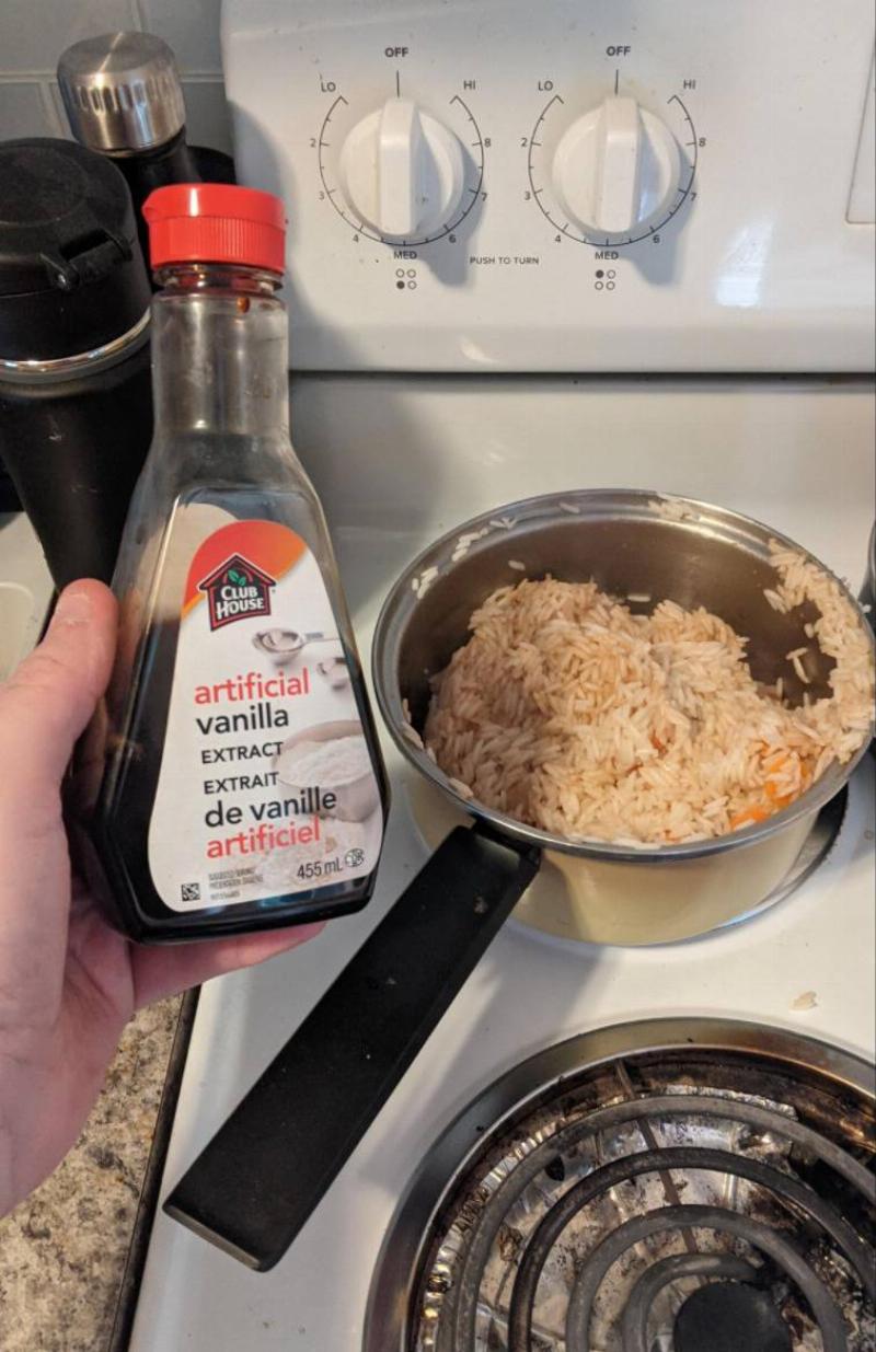 person holding up container of vanilla extract next to pot with rice covered in it