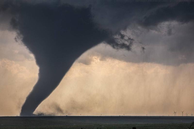 a tornado looking huge next to some wind turbines 