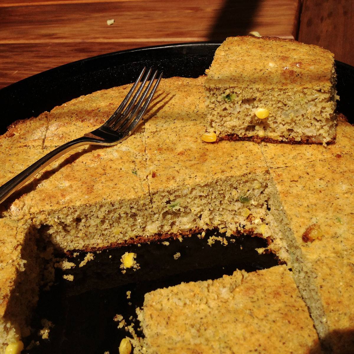 Squares of cornbread are cut out of a pan.