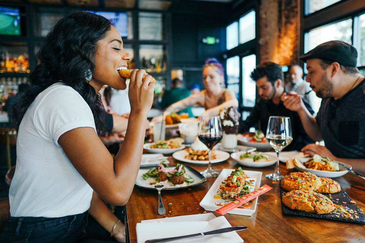 A woman eats at a restaurant with friends.