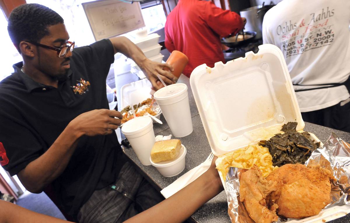 A man and his friend eat fried catfish at a restaurant.