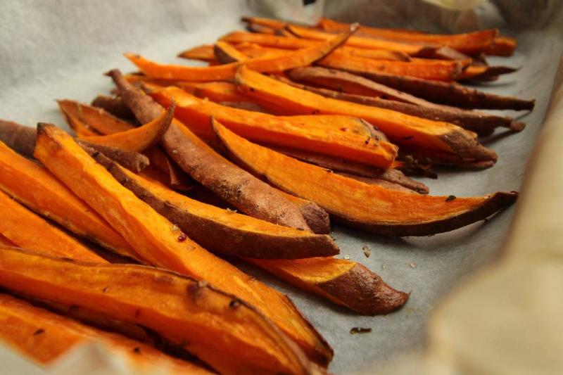 Sweet potato fries are lined on a tray.