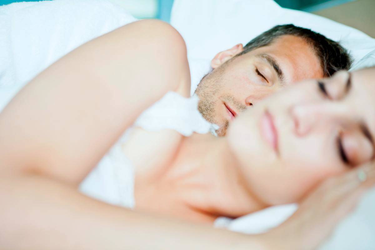 man and woman sleeping in bed with woman out of focus