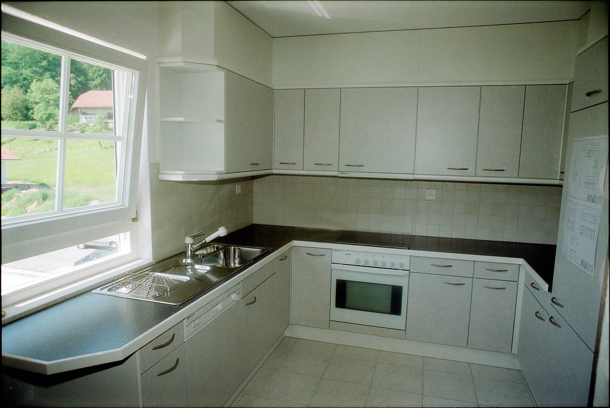 This 1996 kitchen has white cabinets, oven, and refrigerator.