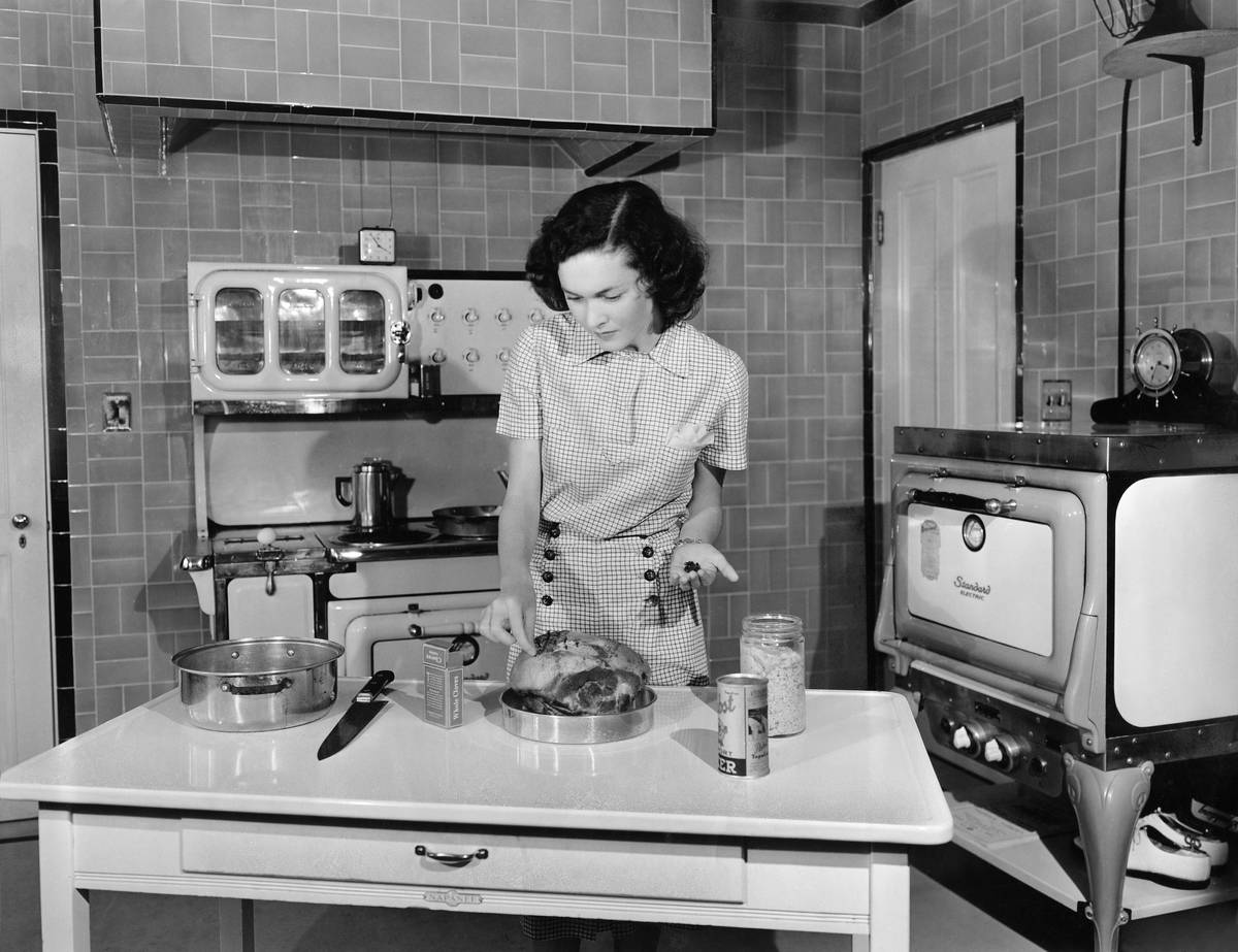 A woman cooks in her kitchen in 1938.