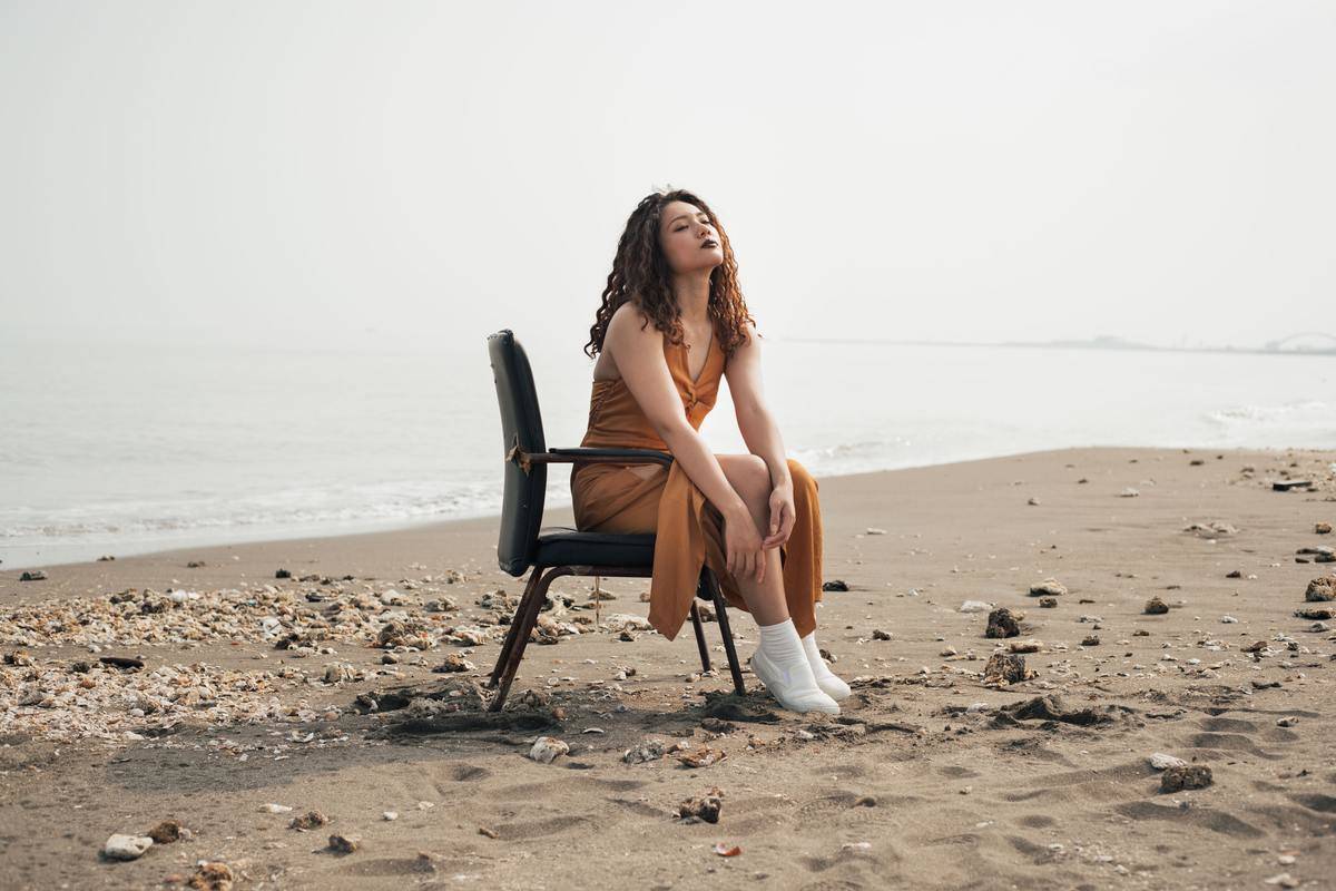 a girl sitting on a chair at the beach