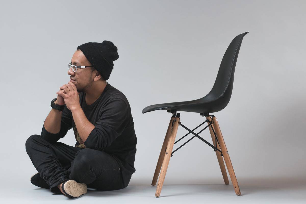 a man sitting cross-legged next to a chair
