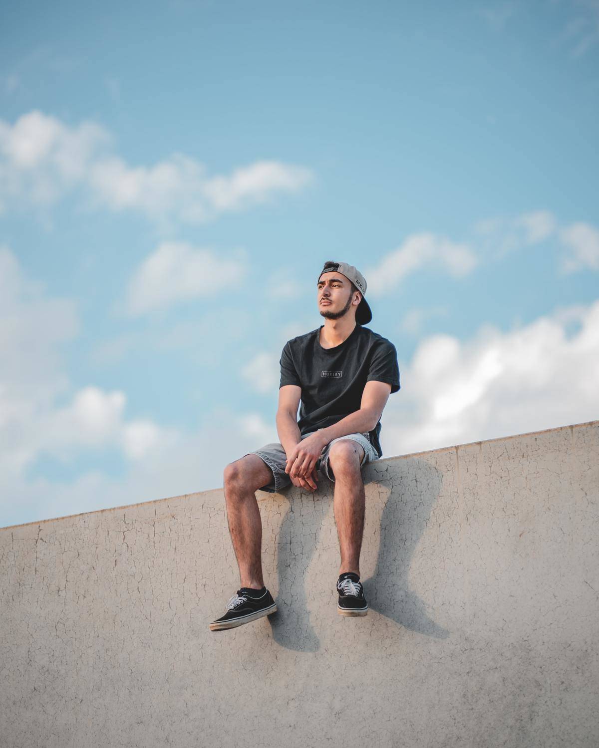 a man sitting on a wall with legs spread out