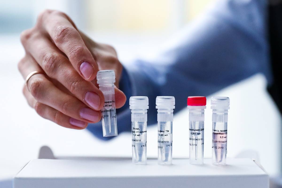 A researcher picks up a vial of DNA for forensic testing.