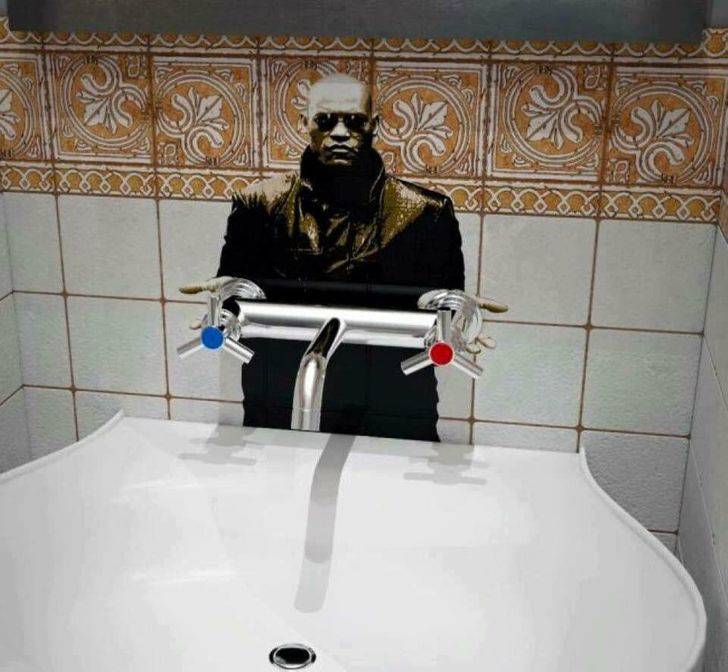 Public bathroom graffiti: Morpheus cutout attached to taps with blue (for cold water) and red (for hot water) 