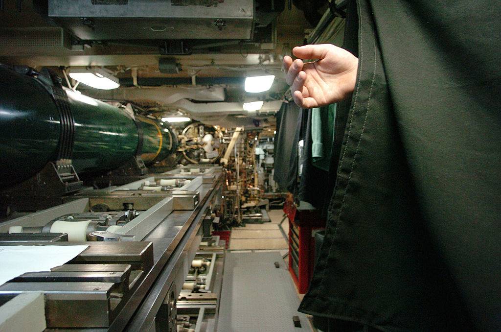 A sleeping sailor's hand hangs from a bunk bed in the missile room