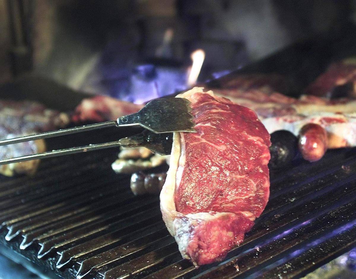 A steak of Argentine beef is put on the grill of a barbecue restaurant in Buenos Aires, Argentina, 08 November 2000.
