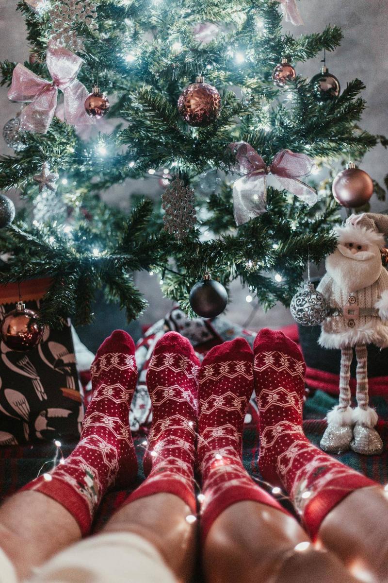 Decorated Christmas tree with people with red socks sitting under it. 