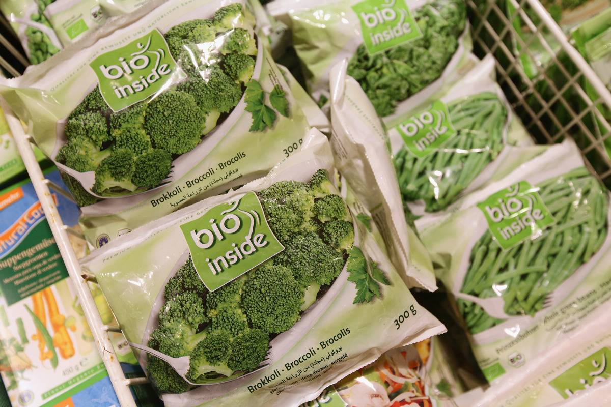 Bags of frozen broccoli in a store freezer