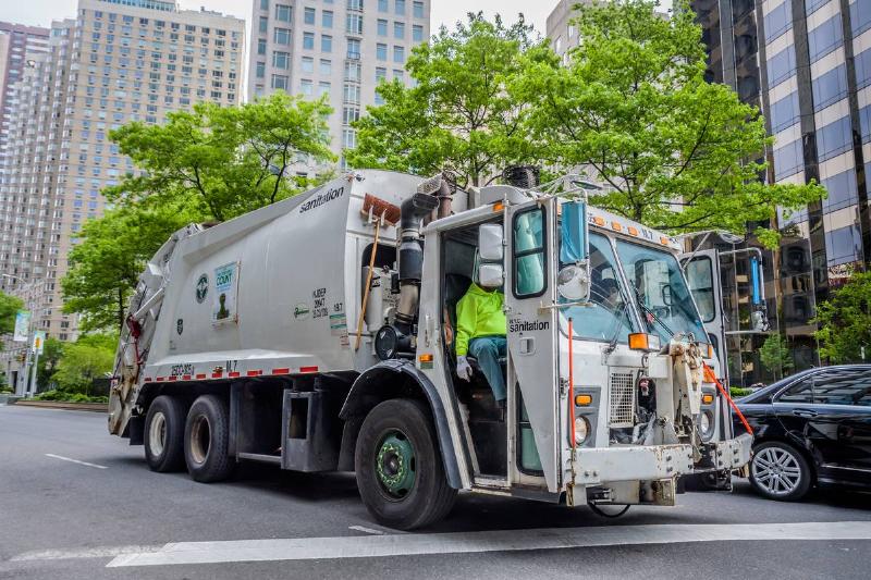 A garbage truck driving around the almost empty streets of...
