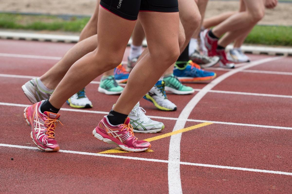 People's feet in a line all wearing running shoes at start line for track and field