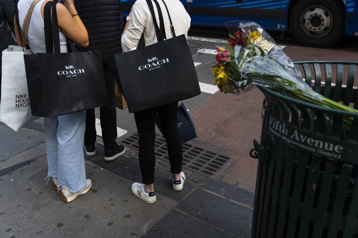 Pedestrians carry Coach branded shopping bags on 5th Avenue in New York, U.S