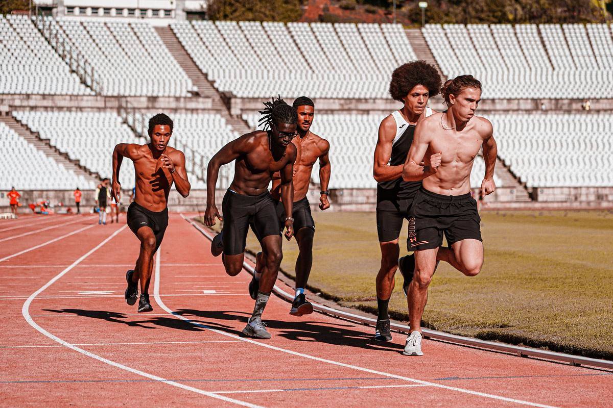 Young men running shirtless around track 